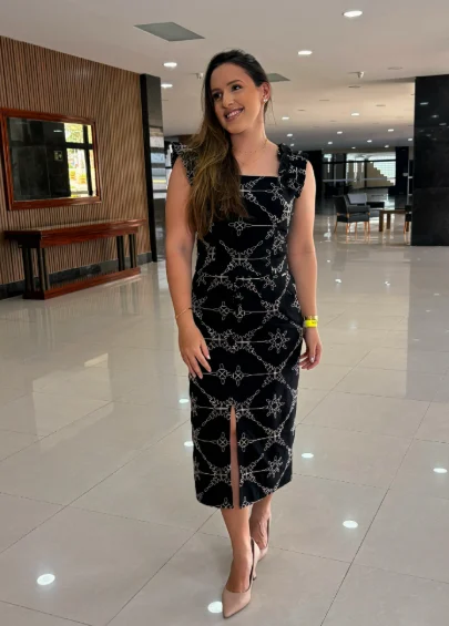 Caroline Marinho de corpo inteiro, com vestido preto estampado